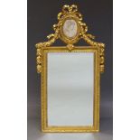 A gilt mirror, in the Louis XVI taste, late 20th Century, the pierced foliate crest, inset with oval