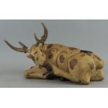 An Indian carved and painted model of a seated cow, with horn antlers, 49cm longPlease refer to