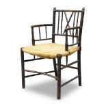 An ebonised Sussex style chair, late 19th Century, with faux bamboo frame above rush seat, raised on