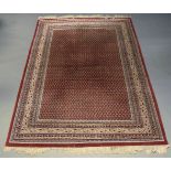 An Indian woolen carpet, mid-20th century, the central reserve densely decorated with lozenge motifs