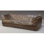 A large brown leather sofa, c.1980, with single shaped cushion, set within a rectangular frame, 69cm