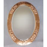 An Arts and Crafts oval copper mirror, early 20th Century, the hammered border with repoussé work