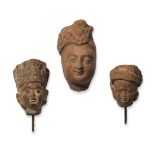 Three small red stone heads, India, 10th-12th century, one with finely moulded features, two with