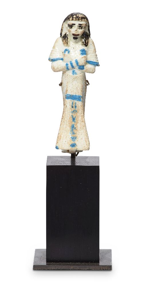 An Egyptian-style bichrome glazed faience shabti wearing a wig, details in turquoise, with single