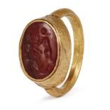 A gold Roman ring with carnelian intaglio of two figures and a child, 1st-2nd century A.D., with