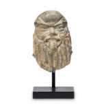 An Egyptian small stone carved head of Bes, possibly New Kingdom, 18th Dynasty, shown with