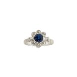 A sapphire and diamond cluster ring, the central circular sapphire to a brilliant-cut diamond