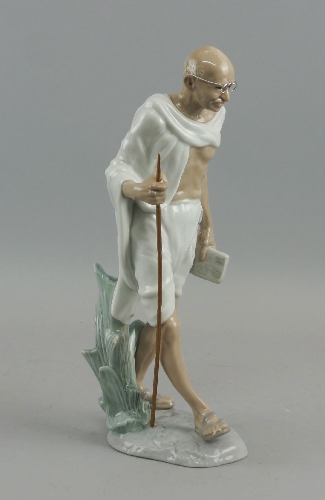 A Lladro porcelain figure of Gandhi, late 20th century, modelled with a book and staff in his hands,