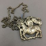 A Chinese white metal pendant necklace formed as a figure riding a dragon
