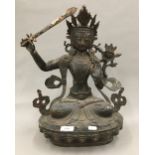 A large Eastern bronze deity holding a with sword