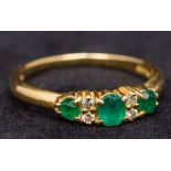 An 18 ct gold diamond and emerald ring The three emeralds interspersed with small diamonds.