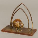 An early 20th century desk stand The bakelite plinth mounted with a small model chick,