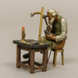 A cold painted bronze figure Modelled as a cobbler at work. 5 cm wide.