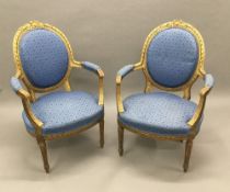 A pair of Louis XV style upholstered giltwood open armchairs Each tied wreath topped padded oval