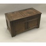 An 18th century oak two panelled coffer The panelled hinged rectangular top above the carved frieze