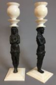 A pair of ivory mounted figural bronze cast candlesticks The turned socles supported on classical