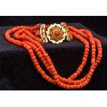 A three strand coral bead necklace Set with a cabochon coral mounted 18 ct gold clasp.