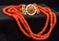 A three strand coral bead necklace Set with a cabochon coral mounted 18 ct gold clasp.