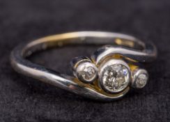 An 18 ct white gold three stone diamond crossover ring The central stone approximately 0.25 carat.