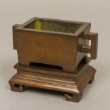 A Chinese patinated bronze censer on stand Of squat rectangular form with angular handles,