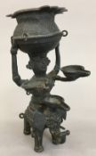 An Indian cast bronze oil lamp Worked as a figure carrying a vessel supported on an elephant. 16.