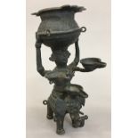 An Indian cast bronze oil lamp Worked as a figure carrying a vessel supported on an elephant. 16.