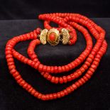 A three strand coral bead necklace Set with a cabochon coral mounted 18 ct gold clasp. 38 cm long.
