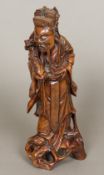 A Chinese carved wooden figure of an immortal Modelled in flowing robes holding a carved ruyi