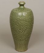 A Chinese celadon glazed pottery vase Decorated in the round with scrolling foliage. 30 cm high.