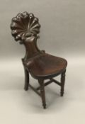 A 19th century mahogany hall chair The shell carved back above the solid seat,