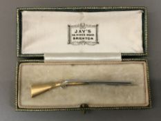 A gentleman's bi-colour 9 ct gold pin Formed as a double barrelled shotgun. 7 cm long.