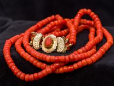 A three strand coral bead necklace Set with a coral mounted 18 ct gold clasp.
