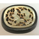 A small Chinese pierced jade panel Of rounded rectangular form, carved with a bat and a dragonfly,