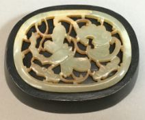 A small Chinese pierced jade panel Of rounded rectangular form, carved with a bat and a dragonfly,