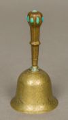 A 19th century Persian brass hand bell With engraved scrolling floral designs and set with