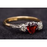 An 18 ct gold diamond and garnet ring The central heart shaped garnet flanked by two diamonds.