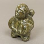 An Inuit carved hardstone figure Worked as a mother carrying her child. 10 cm high.