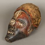 An African tribal carved wooden mask With traces of original paint pigment and mounted with an