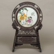 A Chinese porcelain mounted carved hardwood table screen The circular porcelain panel decorated
