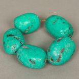 Five large turquoise beads Of natural rough form. The largest 5.5 cm long.