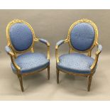 A pair of Louis XV style upholstered giltwood open armchairs Each tied wreath topped padded oval