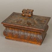 An early 19th century carved wooden box and cover The domed removable lid with flowering urn finial,