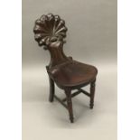 A 19th century mahogany hall chair The shell carved back above the solid seat,