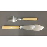 An engraved hallmarked silver fish slice and fork with ivory handles,
