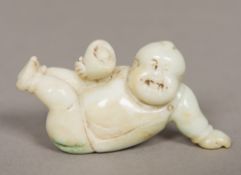 A Chinese carved pale jade figure Worked as a boy holding a nest enclosing an egg. 8 cm long.