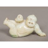 A Chinese carved pale jade figure Worked as a boy holding a nest enclosing an egg. 8 cm long.