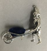 A silver model of a gnome and wheelbarrow