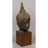 A Chinese cast bronze Buddha's head, later mounted on a wooden plinth base. 18 cm high overall.