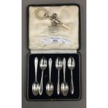 A cased set of silver teaspoons and a silver baby's rattle