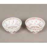 A pair of Chinese porcelain tea bowls, decorated with iron red lotus strapwork. 9 cm diameter.